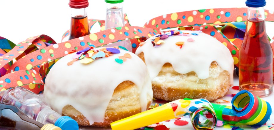 Berliner mit Zuckerguss, Likörflaschen und Tröten auf Konfetti