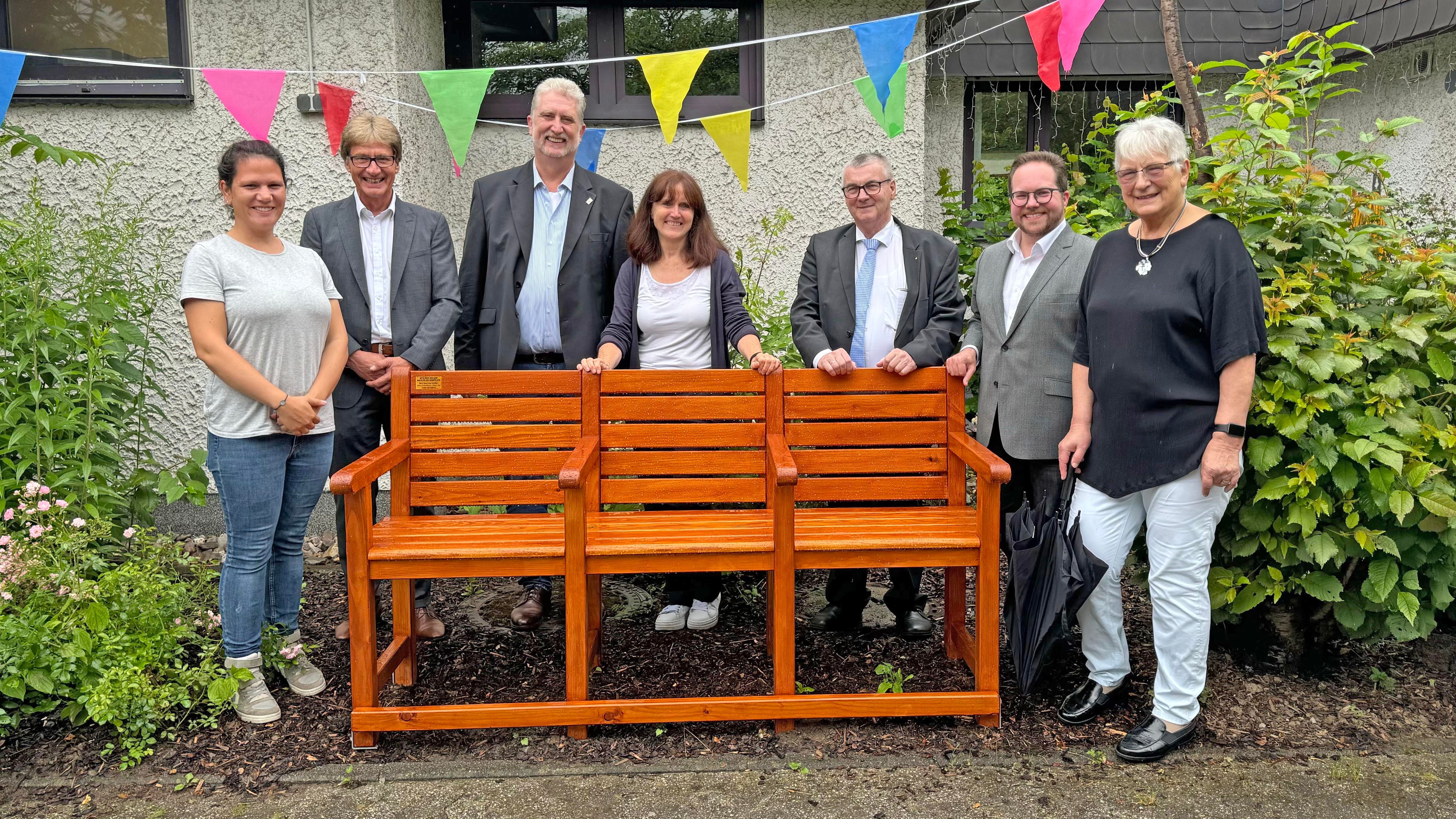 Landrat Dr. Alexander Saftig (3.v.r.), der Erste Kreisbeigeordnete Pascal Badziong (2.v.r.), Projektleiterin „Bewegung in die Dörfer“ Lea Bales (Mitte) und Berthold Nick (2.v.l.) von der evm haben jüngst die Seniorenbank an die Stadt Vallendar übergeben. Hierüber freuten sich der Pfarrer der Evangelischen Kirchengemeinde Vallendar Berg Gerd Götz (3.v.l.), Laura Steffen (links) und die Vallendarer Bewegungsbegleiterin Ingrid Brennecke (rechts). 