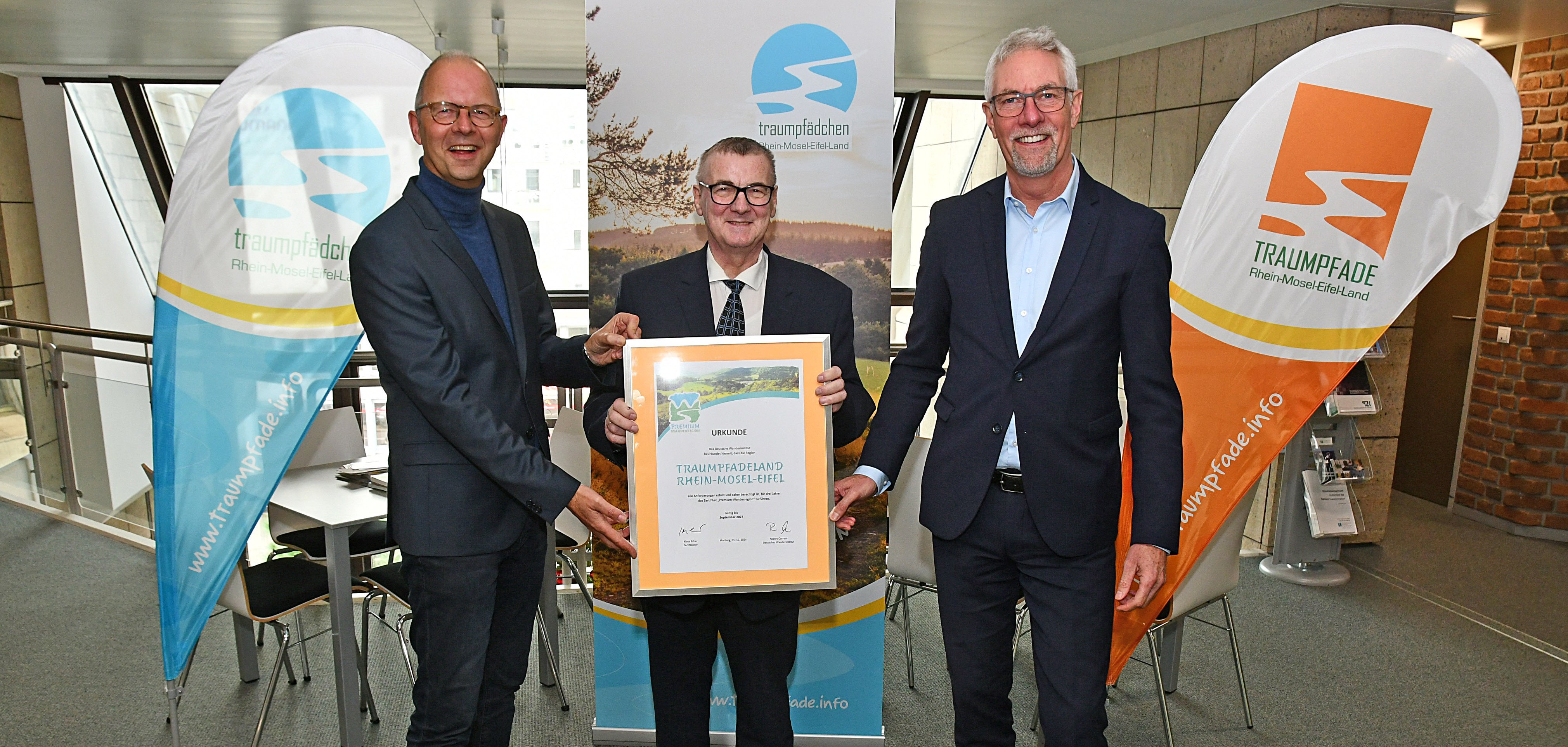 Landrat Dr. Alexander Saftig (Mitte), Henning Schröder (rechts) und Michael Schwippert freuen sich über die erneute Auszeichnung als Premium-Wanderregion. 