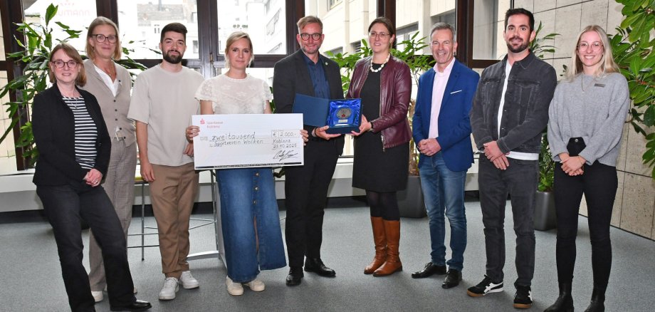 Die 1. Vorsitzende des SV Wolken Nancy Stephan (4.v.l.) nimmt die Ehrung von Landrat Marko Boos (Mitte) entgegen. 