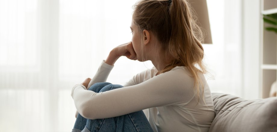 Upset woman sitting on couch alone at home Upset woman sitting on couch alone at home