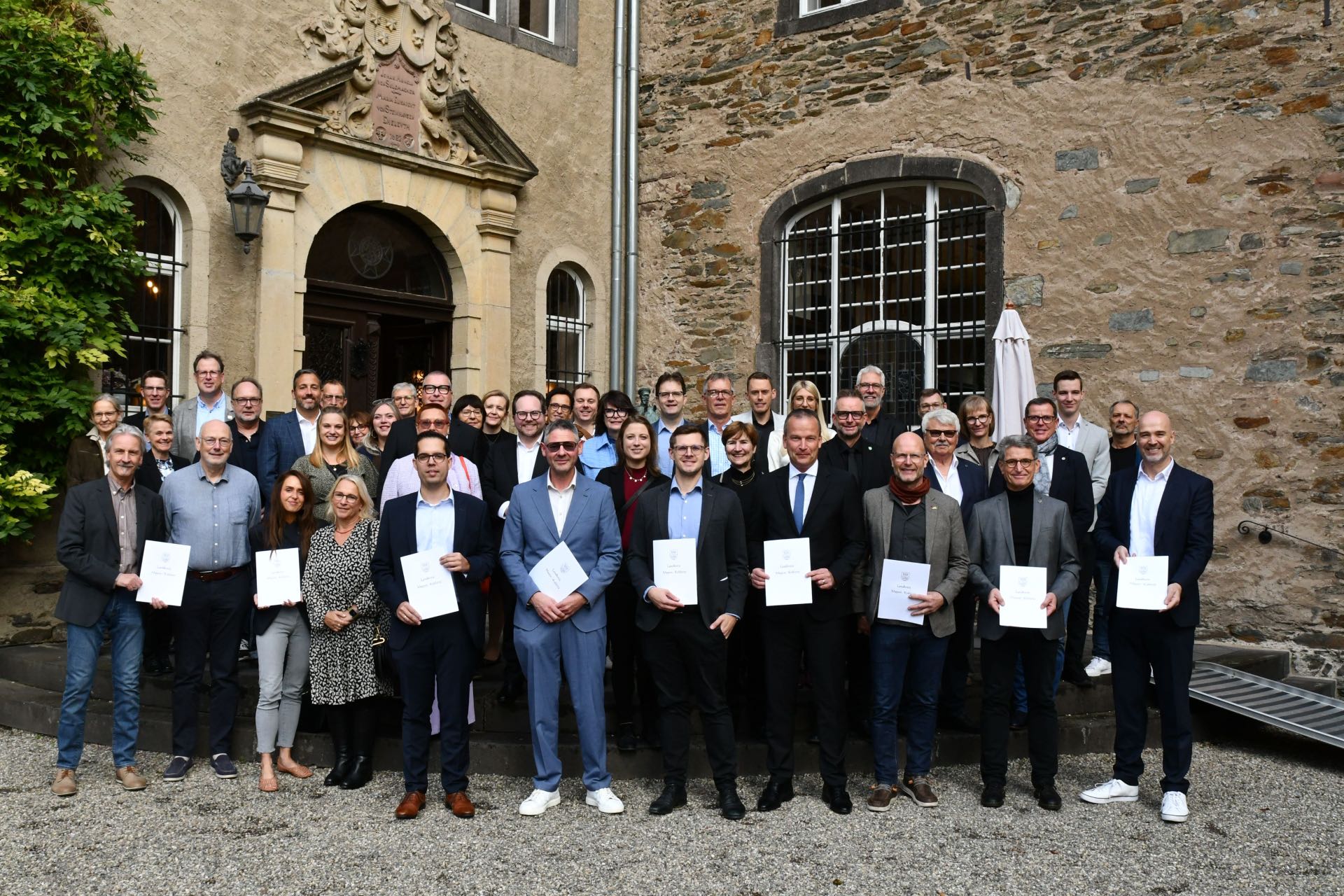 Die Preisträger des Wettbewerbs „MYK Zukunft mit Familie“ gemeinsam mit Landrat Marko Boos (2. Reihe, 3. von rechts), kommunalen Vertretern und weiteren Gästen aus Politik und Wirtschaft auf Burg Namedy. 